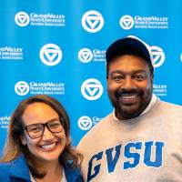Two event attendees smiling and posing for photo in front of GV back drop